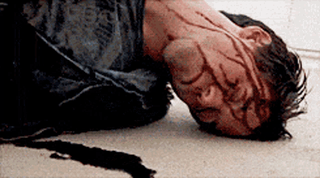 a man laying on the ground with blood on his face