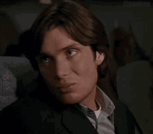 a man in a suit and tie is sitting on an airplane looking at the camera .