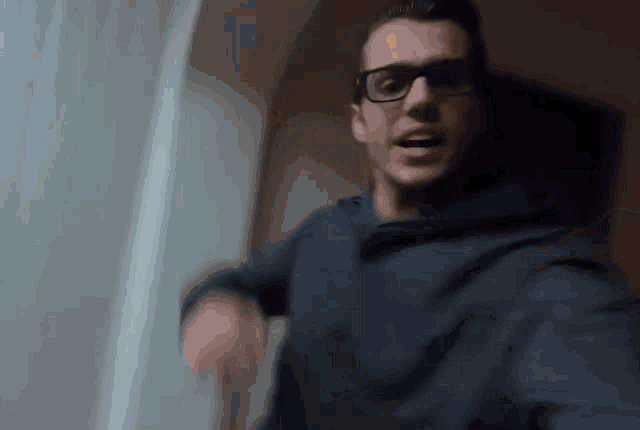 a blurry picture of a man wearing glasses and a blue sweatshirt