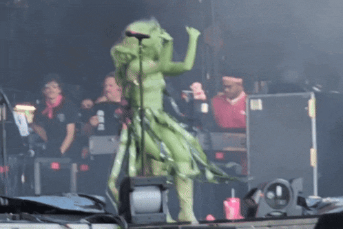 a woman with green hair singing into a microphone on stage