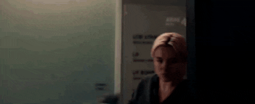 a woman with a towel on her head is standing in a dark room in front of a mirror .