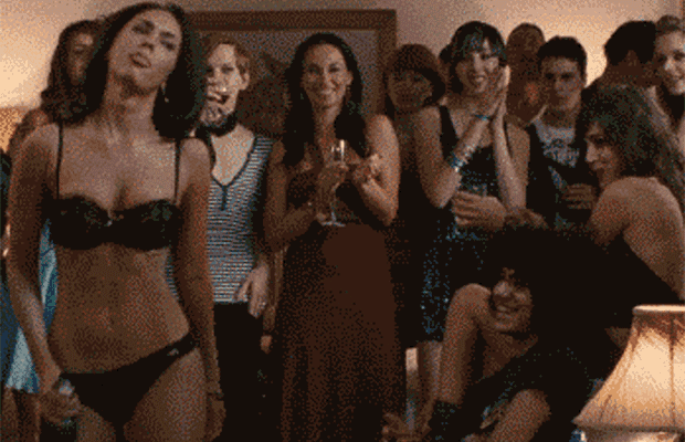 a woman in a bra and panties stands in front of a crowd of people