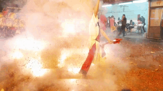 a man in a red apron is standing in front of a huge explosion