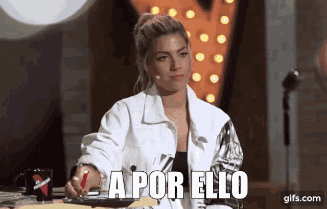 a woman in a white jacket is sitting at a table with the words a por elo in front of her