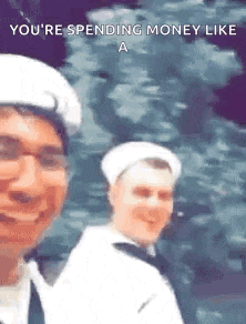a man in a white hat is taking a selfie with another man in a navy uniform .