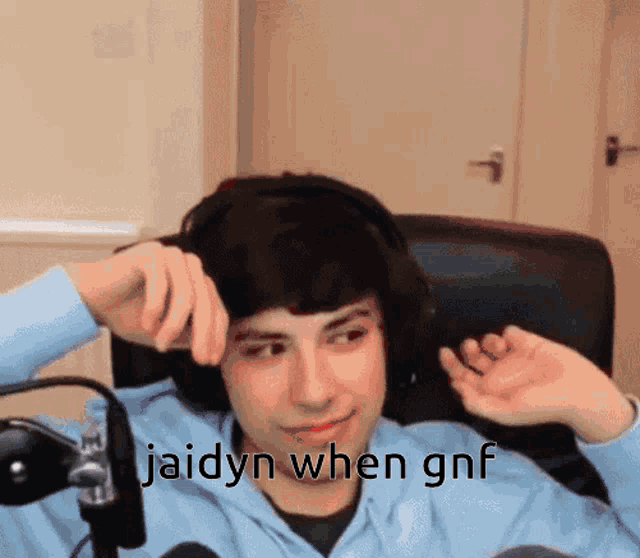 a man wearing headphones is sitting in front of a microphone with the words jaidyn when gnf written below him