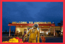 two astronauts are standing in front of a sign that says " welcome to knowhere "