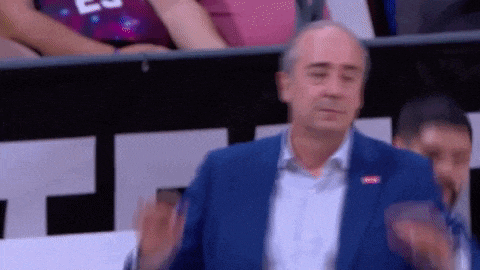 a man in a blue suit is applauding while sitting in the stands .