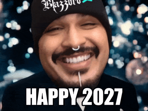 a man with a beard wearing a black beanie and a piercing in his nose says happy 2027