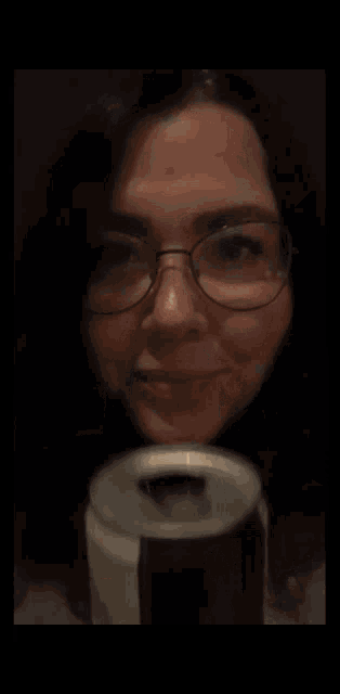a close up of a woman wearing glasses covering her face with her hand