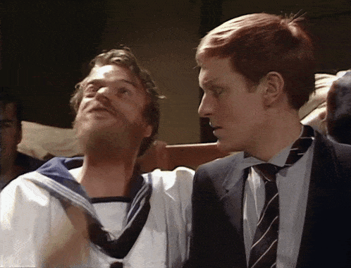 two men are standing next to each other and one is wearing a sailor 's uniform