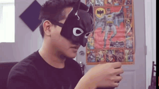 a man wearing a batman mask is sitting in front of a batman poster ..