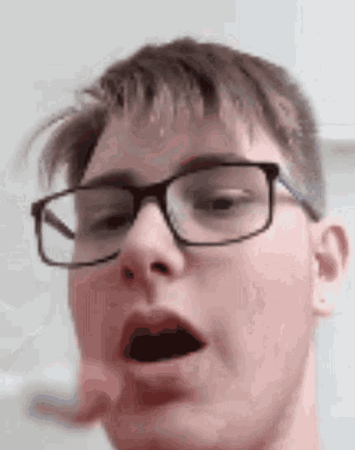 a close up of a young man wearing glasses making a funny face .