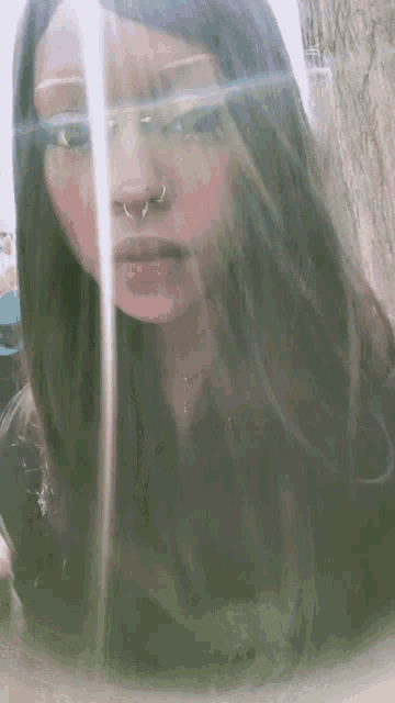 a woman with long hair and a nose ring is looking at the camera