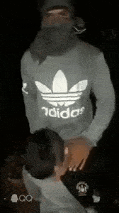 a man in an adidas sweatshirt is giving a woman a blowjob in the dark .