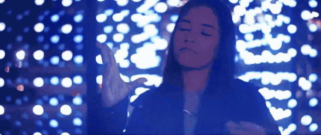 a woman is standing in front of a wall of lights with her eyes closed
