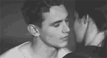 a black and white photo of a woman kissing a man on the neck .