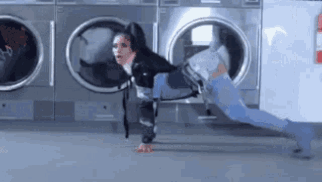 a woman is doing a handstand in front of a washing machine
