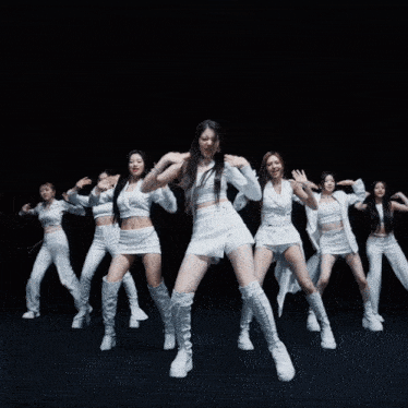 a group of women in white clothes are dancing together
