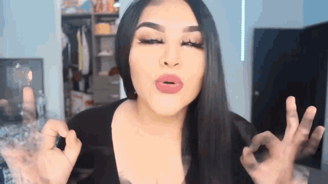 a woman with long black hair is giving an ok sign