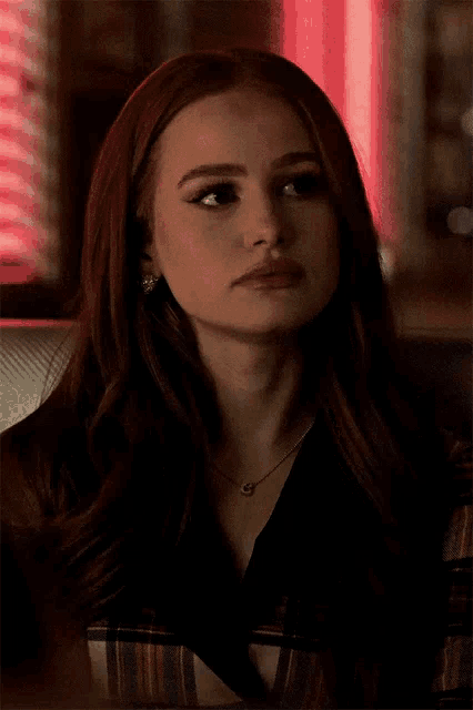 a close up of a woman 's face with red hair and a necklace