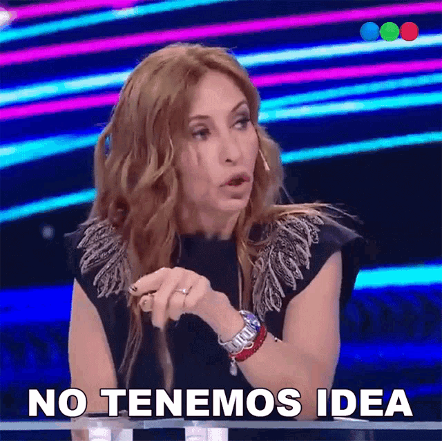 a woman says no tenemos idea in front of a colorful background