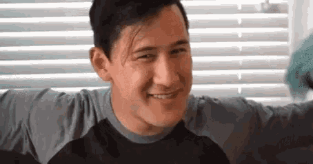 a man is smiling while sitting in front of a window .