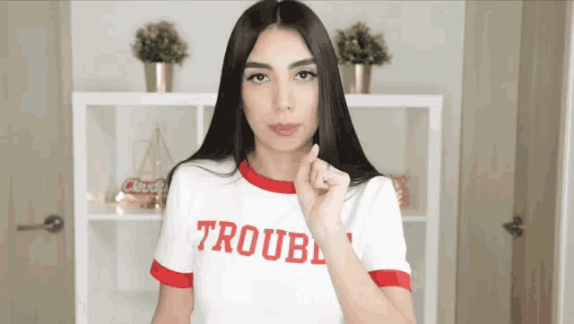 a woman wearing a white shirt that says trouble
