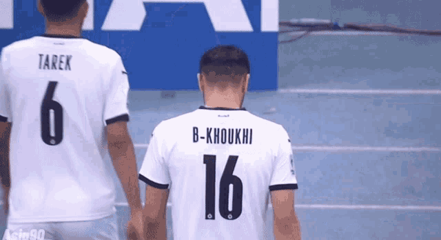 a soccer player wearing a number 16 jersey stands next to another player wearing a number 6 jersey