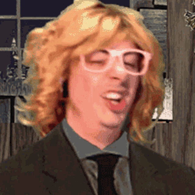a man with blonde hair wearing glasses and a suit and tie