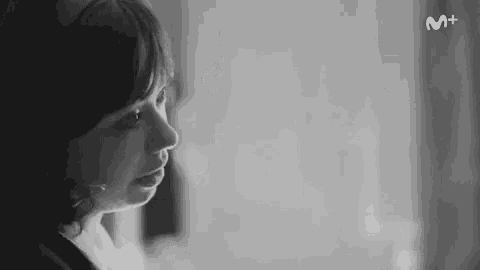 it is a black and white photo of a woman looking out a window .