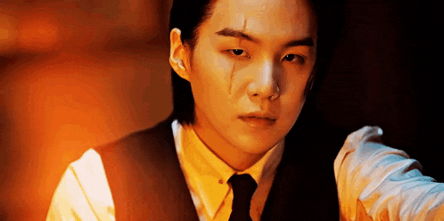 a close up of a man wearing a suit and tie with a tear coming out of his eye .