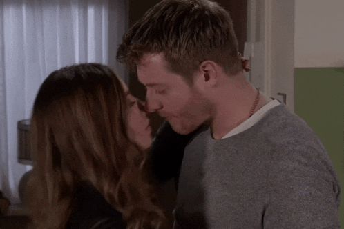 a man and a woman are kissing in a living room