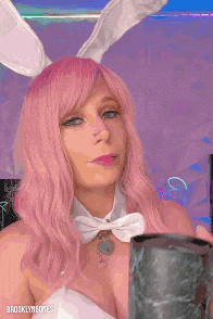 a woman with pink hair and white bunny ears is holding a cup