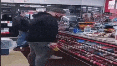 a man wearing a mask is standing in front of a convenience store counter .