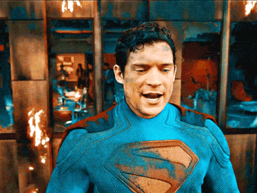 a man in a blue superman costume stands in front of a wall