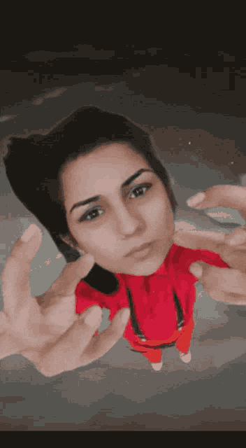 a woman wearing a red shirt and orange pants is giving the middle finger