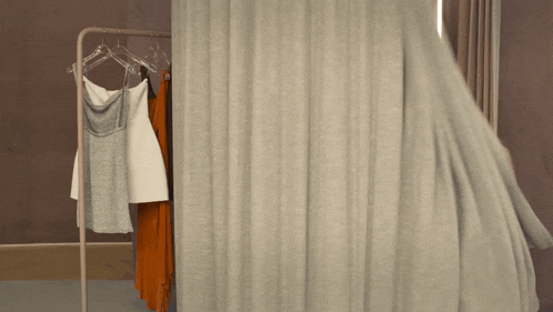 clothes hanging on a rack with a curtain behind it