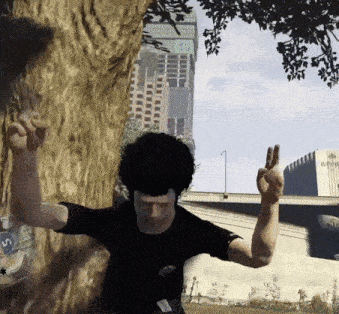 a man in a black shirt is standing next to a tree giving the middle finger