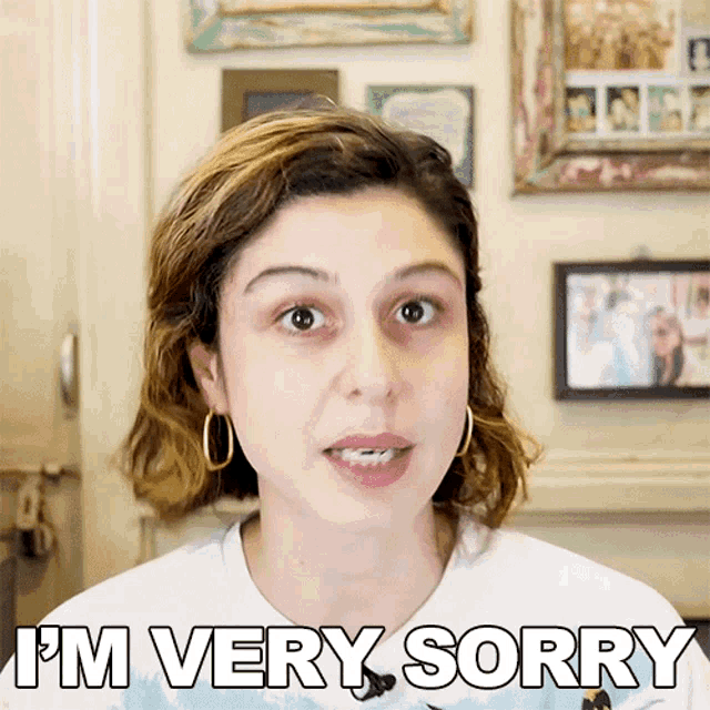 a woman says i 'm very sorry in front of a wall with pictures