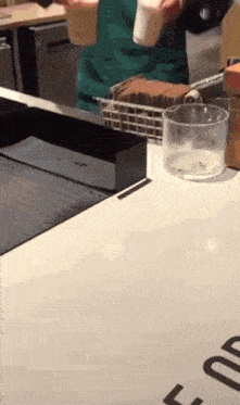 a person in a green apron pouring a drink into a cup