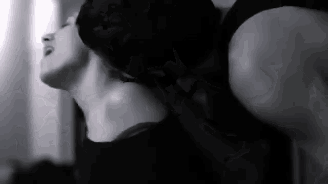 a black and white photo of a man kissing a woman 's neck .