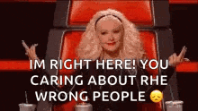 a woman is sitting in a chair with her arms outstretched and giving the middle finger .