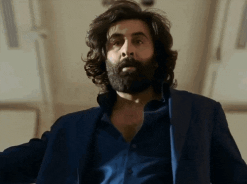 a man with long hair and a beard wearing a blue jacket