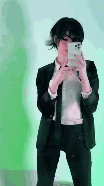 a person in a suit and tie is taking a selfie with their phone .