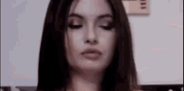 a woman with long hair is making a funny face with her eyes closed .