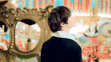 a man is standing in front of a merry go round and looking up .