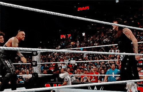 a woman is sitting in front of a crowd with a w logo on the wall behind her