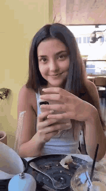 a woman is sitting at a table with a plate of food and a glass of water .