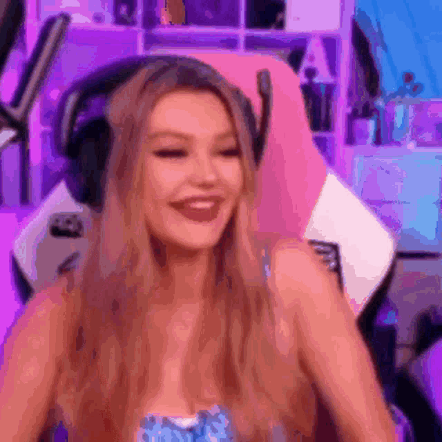a woman wearing headphones is sitting in a pink chair and smiling .